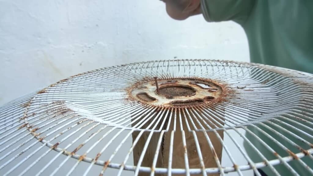 扇風機のカバーを支柱に釘で留めているところ