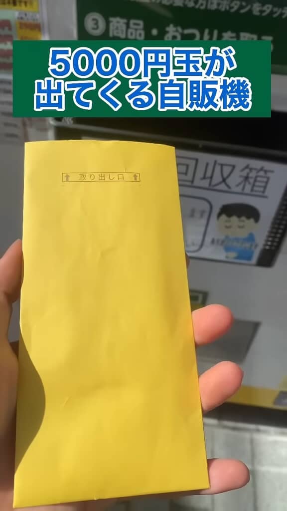 5000円玉が出てくる自販機の取り出し口から黄色い封筒を取り出す様子
