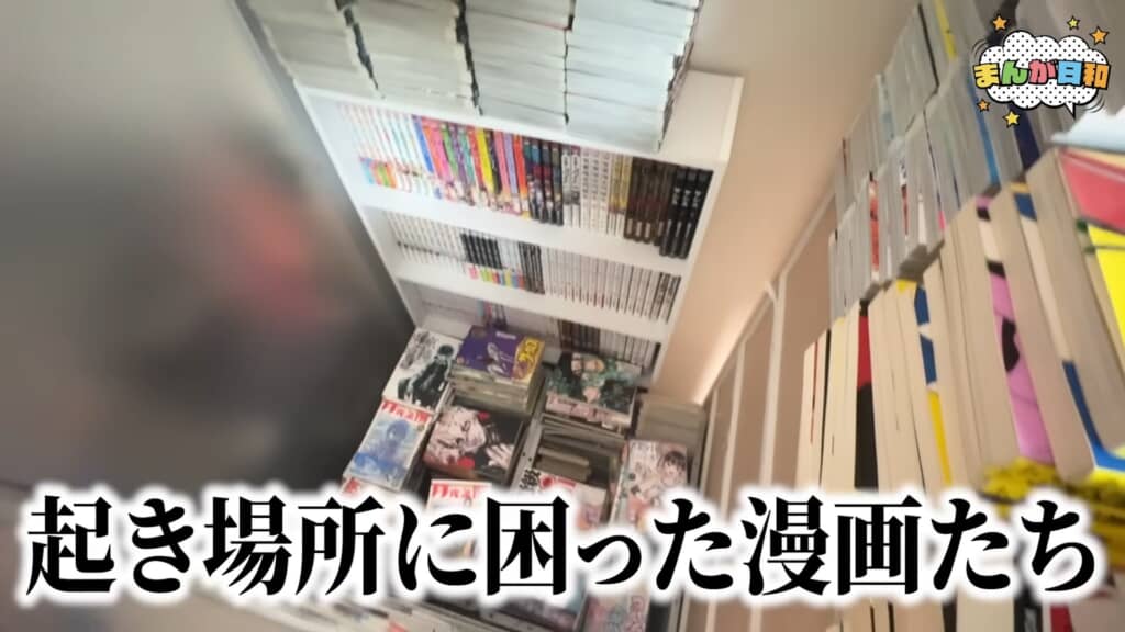 天井近くまで積み上がった漫画本、床置きの本の様子