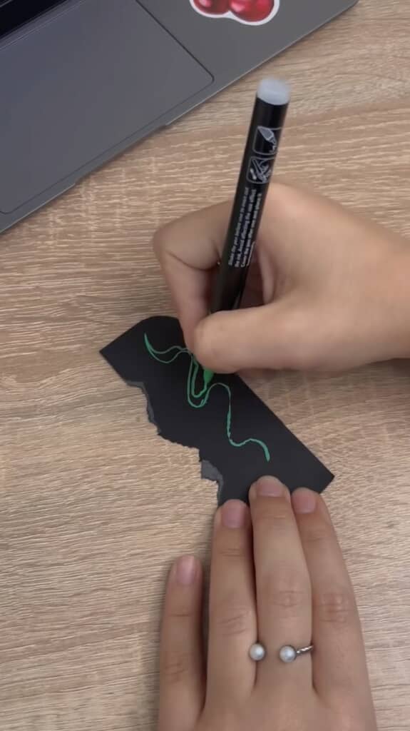スマホケースの形にカットした黒い紙をちぎって絵を描き