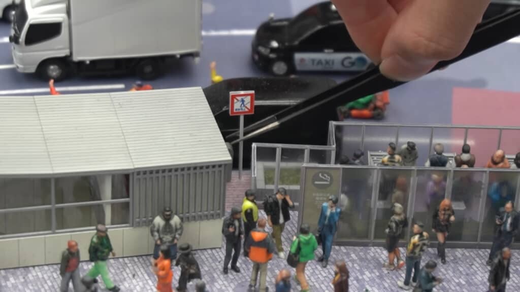 ピンセットで歩行者禁止標識を設置する渋谷ジオラマ制作作業
