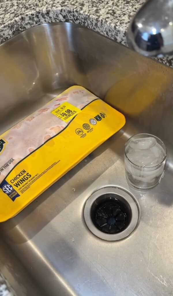 シンクの中に鶏肉のパックと氷水の入ったコップが置かれていました