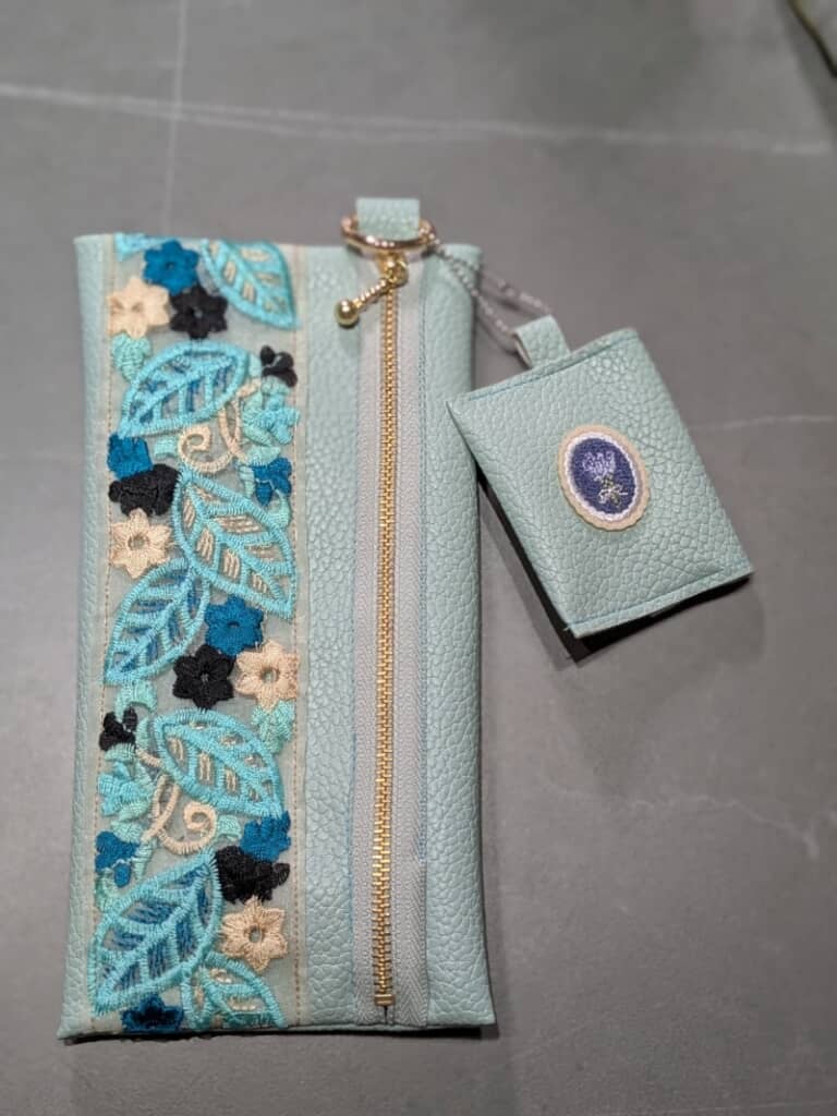 水色の葉と黒・青・ベージュの花が散りばめられたかわいらしい模様のリボン