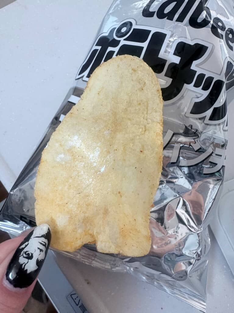 袋半分ぐらいの大きさのポテチを持つマイケルのネイルをした指