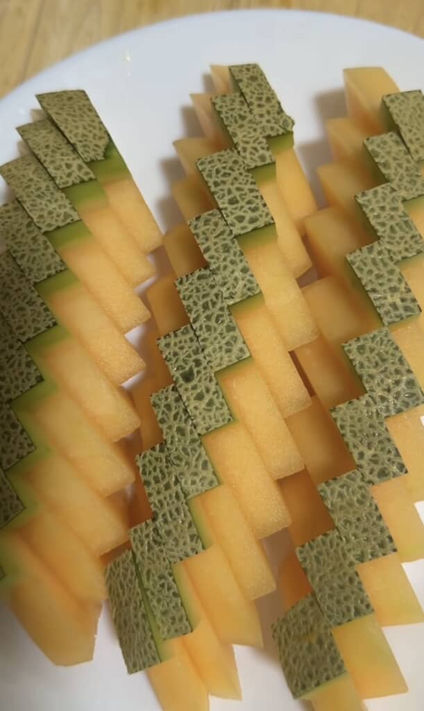 皮を市松模様に残してスティック状に切ったメロンを白い皿に盛り付けた様子