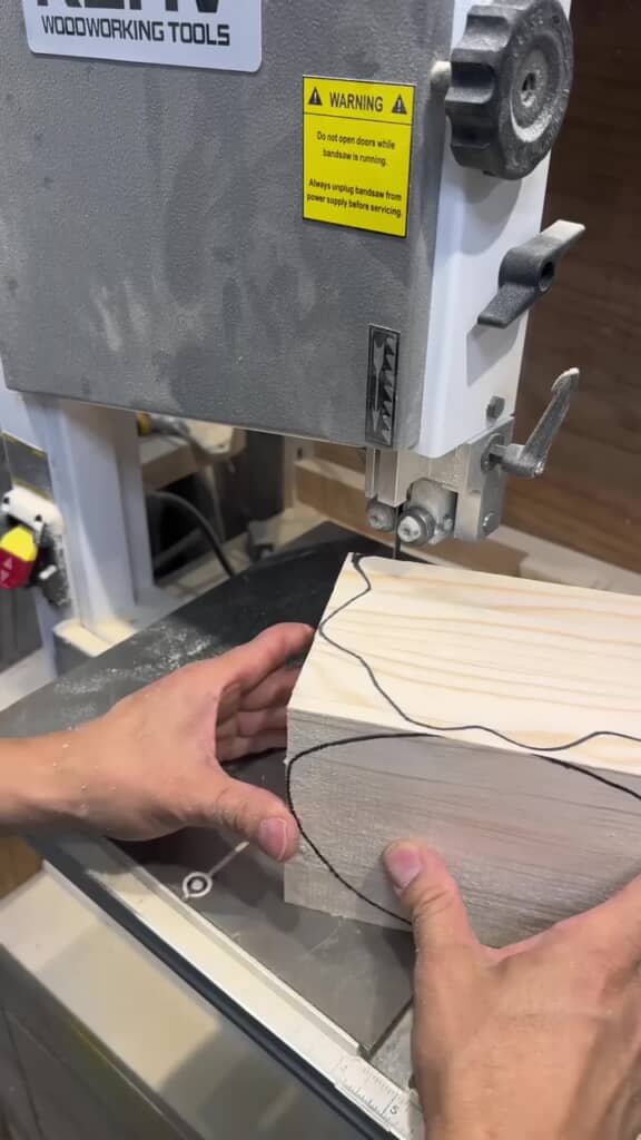 線を引いた木のブロックを電動糸ノコギリで切る