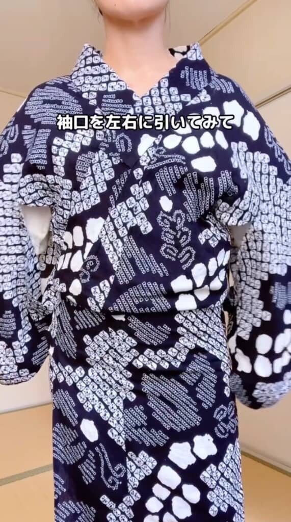袖口を左右に引いて首元を広げる