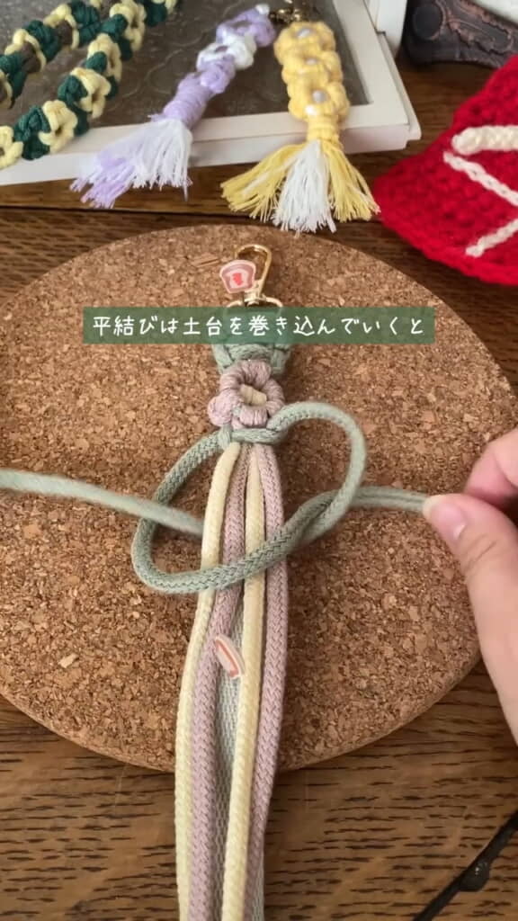 土台を巻き込んで平結びをしつつストラップ上で花を編みます