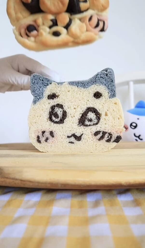 ハチワレ風の食パン断面を手に持ち木製ボードの上に立てた様子
