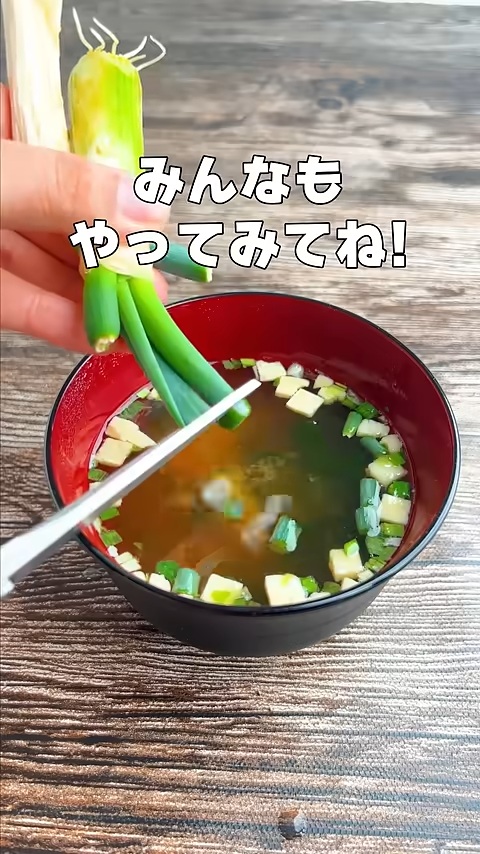 味噌汁の上で容器から取り出したばかりの白ネギをキッチンばさみで切る