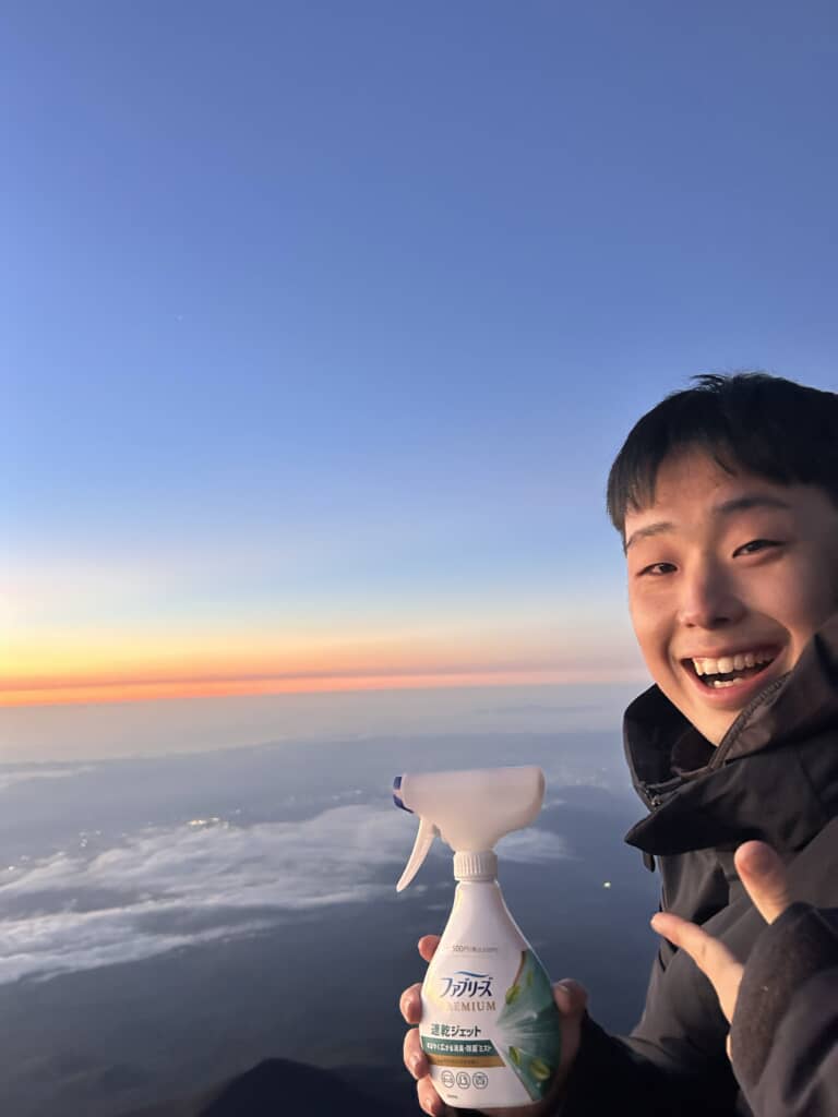 富士山頂でファブリーズ プレミアム速乾ジェットを手に笑顔を見せる男性