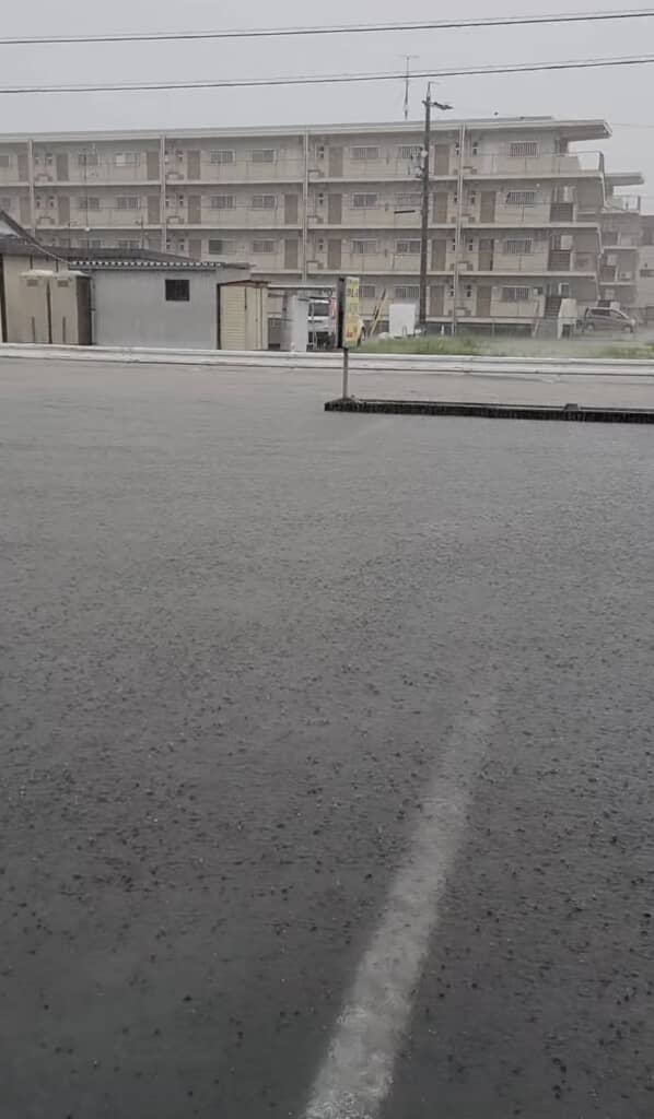 激しい雨で一面が冠水した駐車場と奥に見える集合住宅
