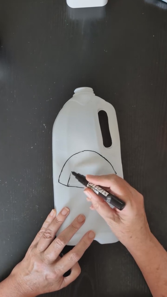 (1/3)持ち手付きの大きなプラスチック容器をきれいに洗って乾燥させ、側面に切り取り線を描いていきます。身近な使用済み容器が、ハロウィーンアイテムへと変身する第一歩(※画像はInstagramアカウント/「Pauline」から)