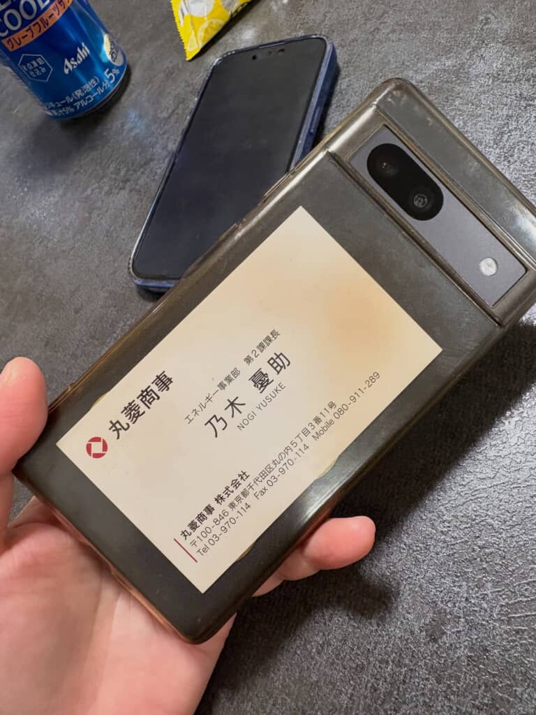 スマートフォンとケースの間に丸菱商事の名刺を挟んでいる様子