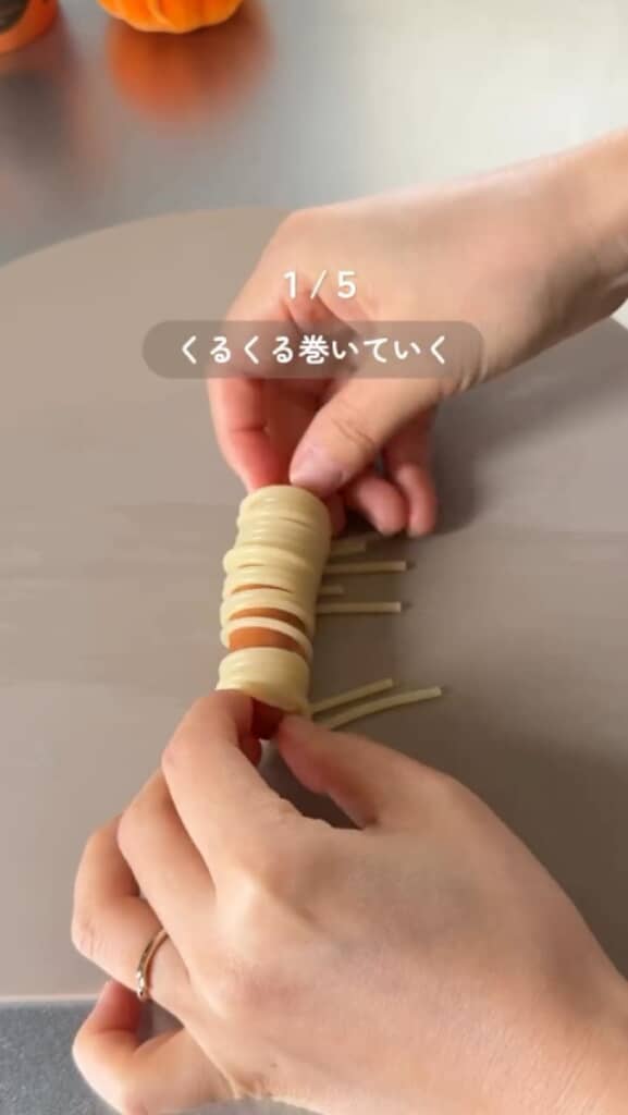 パスタをウインナーに巻き付けていく