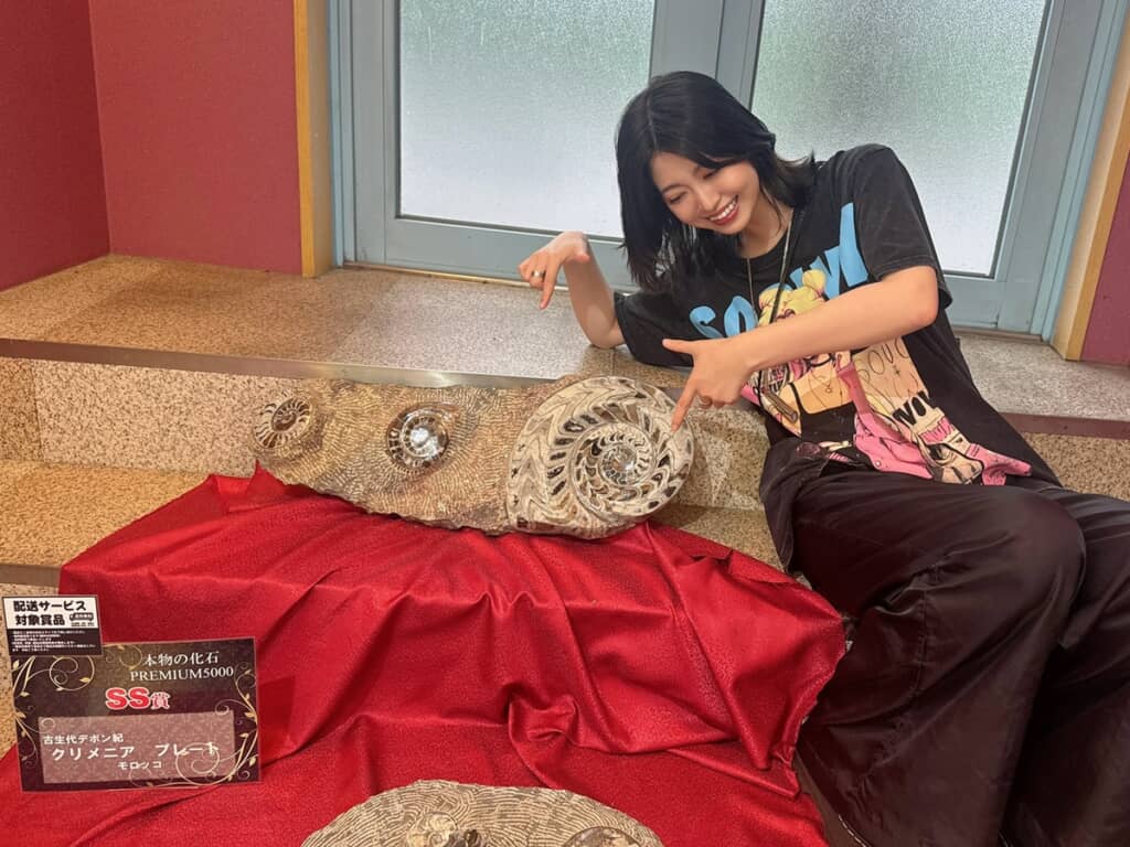 巨大な「古生代デボン紀　クリメニア」のプレートの隣に座る投稿者