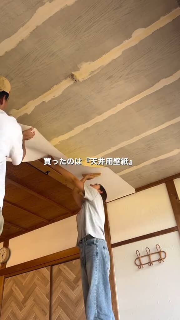 夫に支えてもらいながら壁紙貼り