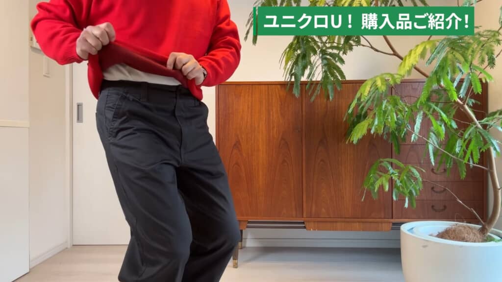 赤いトップスとグレーのパンツを着用し、ユニクロUの購入品を紹介する男性