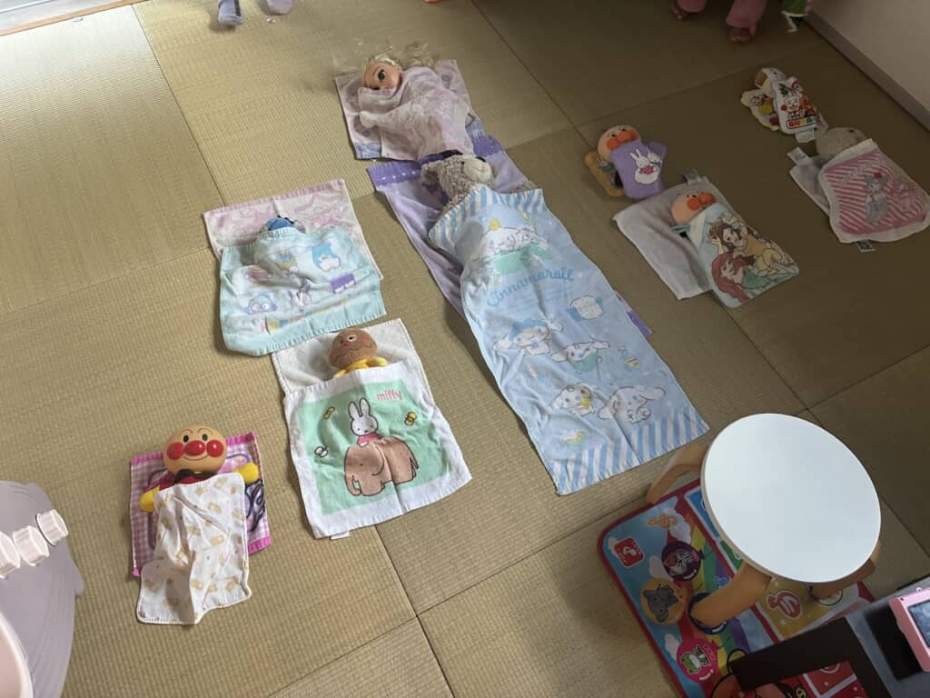 タオルを布団代わりにして寝かしつけられた、アンパンマンやクマのぬいぐるみたち