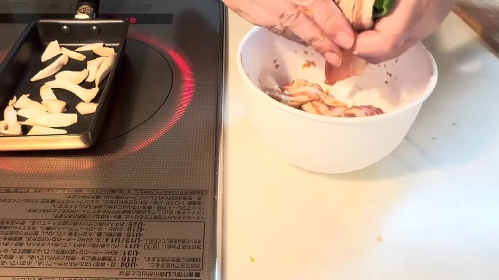 エリンギを炒めながら豚肉でピーマンを巻きます