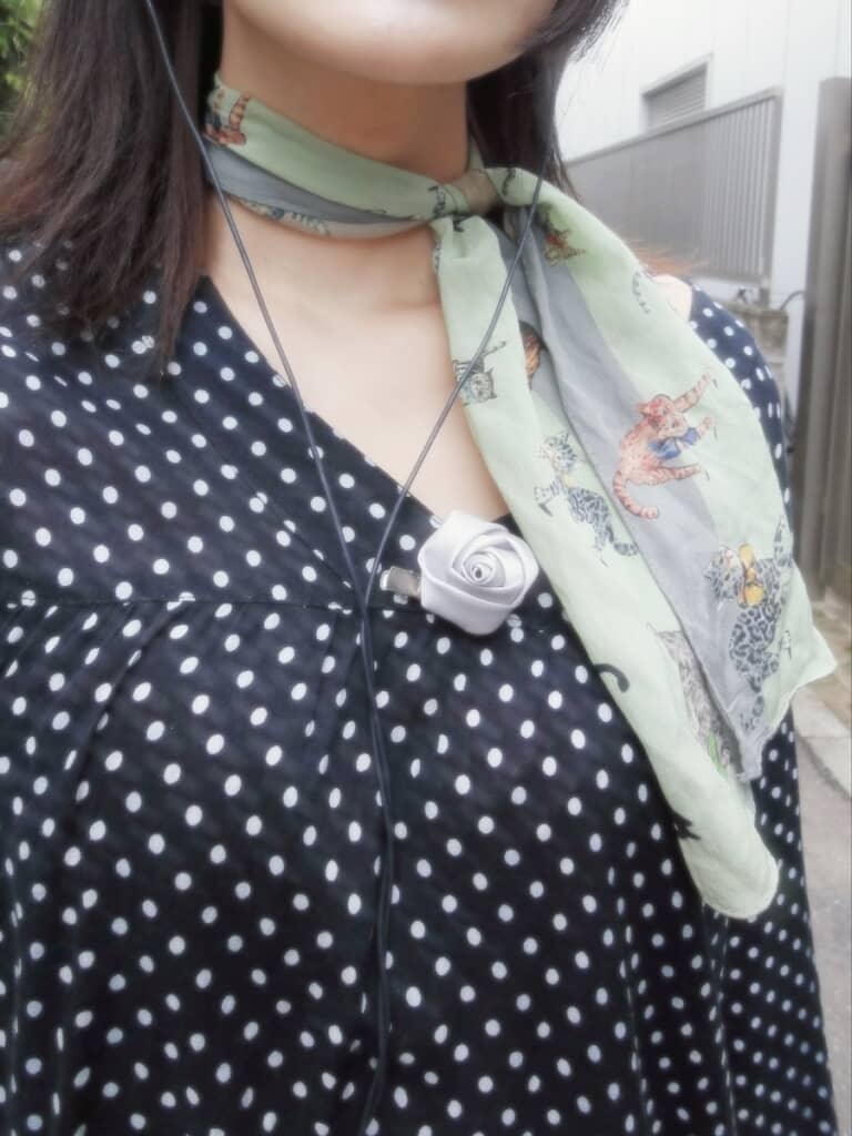 グリーンのスカーフと白いバラのアクセサリーで、顔まわりを華やかに