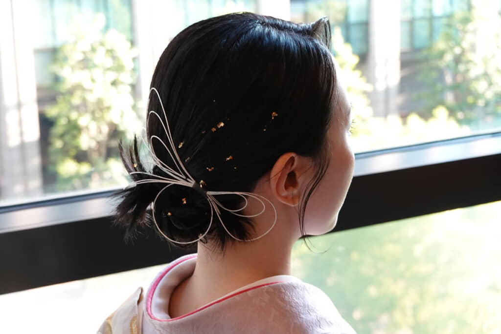 髪には小さな金箔を散らし、水引きをモチーフにしたヘアアクセサリーをプラス