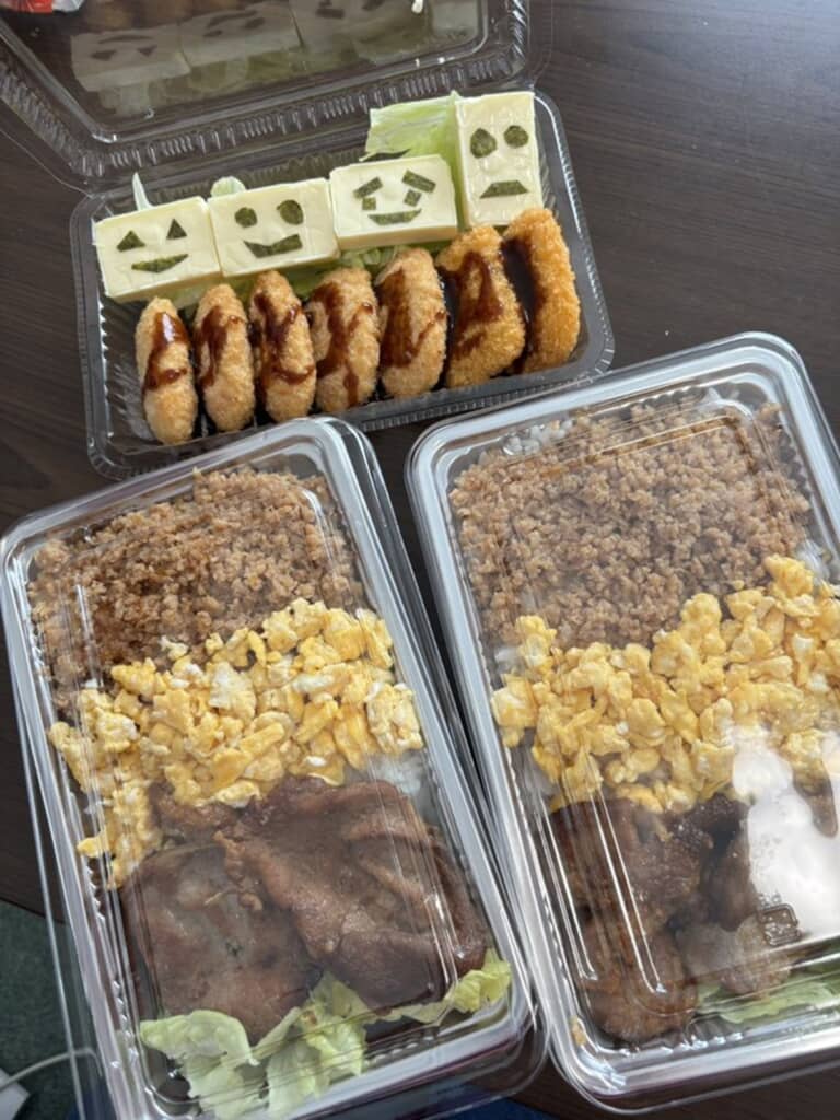 肉料理や卵、揚げ物などがたっぷり。奥には顔が描かれたおかずも並んでいます