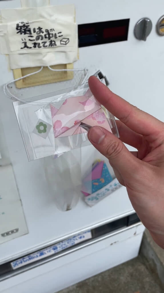 取り出し口から、袋に入った桜柄の折り紙が出てきました（作品名は「ふうせんきんぎょ」）